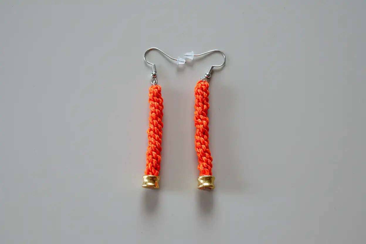 Dettaglio degli orecchini pendenti in Microparacord arancione con monachelle in acciaio inox